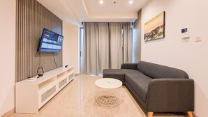A modern living room with a grey sofa, a white TV on a wall, a white console table, and a round coffee table.