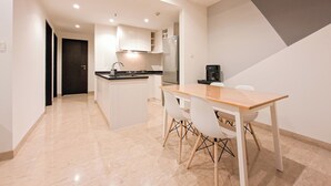 A modern kitchen with a central island, white cabinetry, and a dining area with a wooden table and chairs.