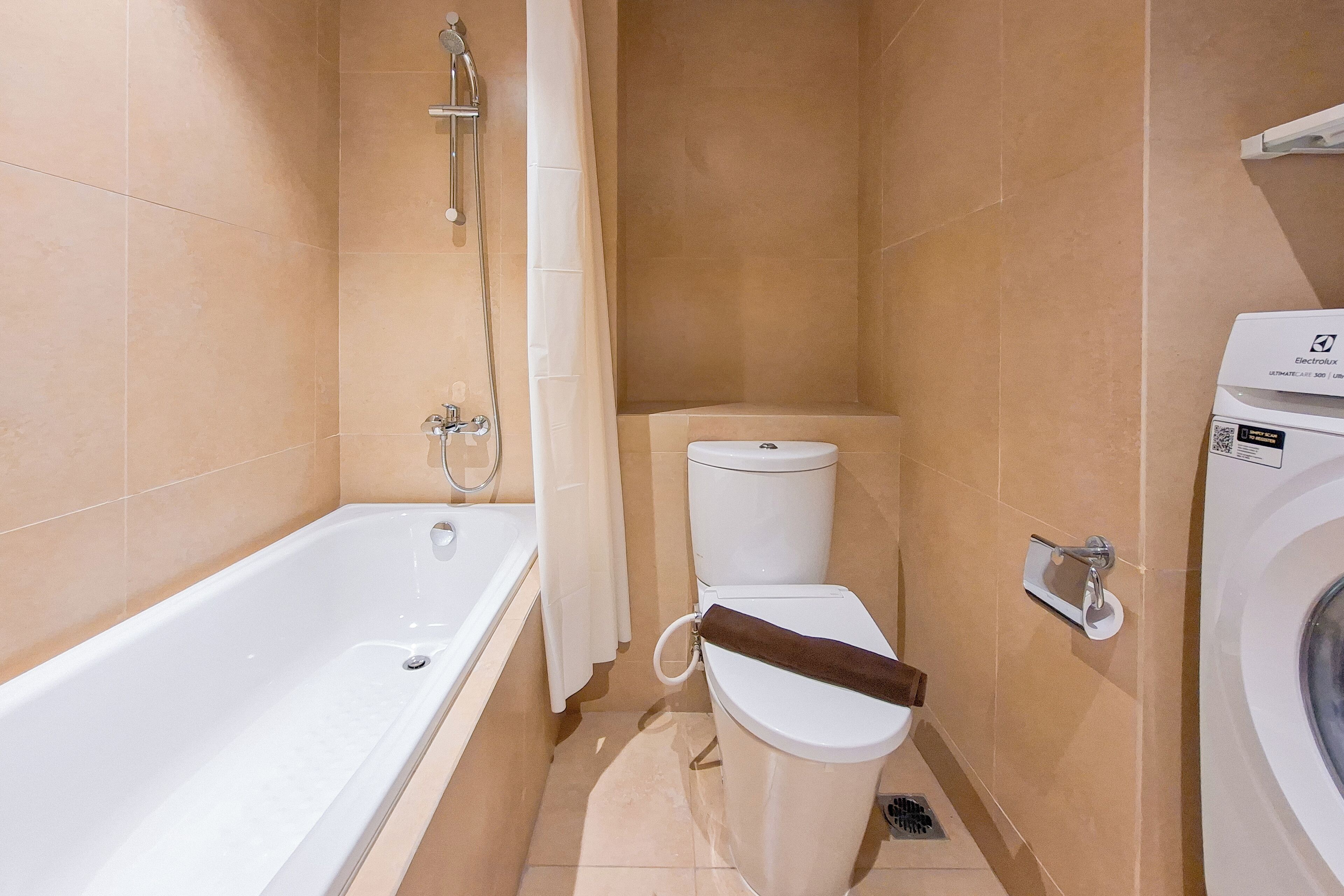 Een badkamer met een bad, toilet en wasmachine.