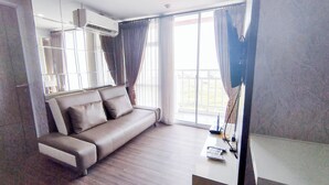 Una habitación de hotel moderna con sofá de cuero, ventanas amplias y un balcón.