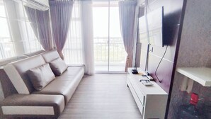 Una sala de estar moderna con un sofá, un televisor de pantalla plana montado en la pared y un balcón con vistas.