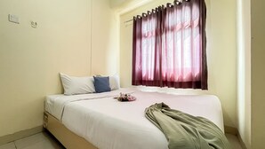 Habitación de hotel con cama, ventana con cortinas, mesita de noche y un interruptor de luz en la pared.