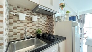 Une cuisine moderne dotée d’un évier en acier inoxydable, d’une cuisinière à gaz et d’un dosseret carrelé.