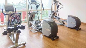 Une salle de sport équipée d’appareils de cardio, d’un vélo d’appartement et d’un rameur.