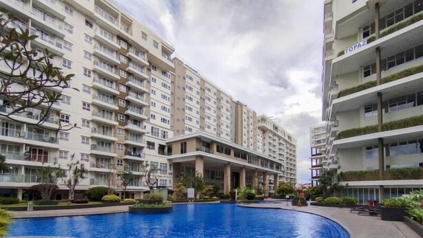 Un edificio residencial con varios balcones, piscina y abundante vegetación.