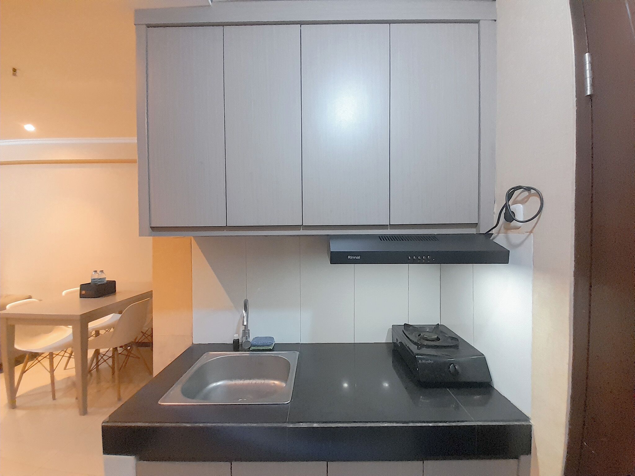 A compact kitchen with a sink, a stove, and a cabinet above.