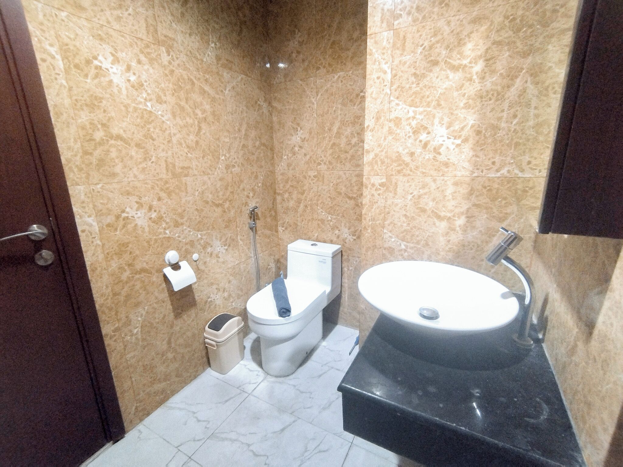 Un baño pequeño con inodoro, lavamanos y paredes de mármol.