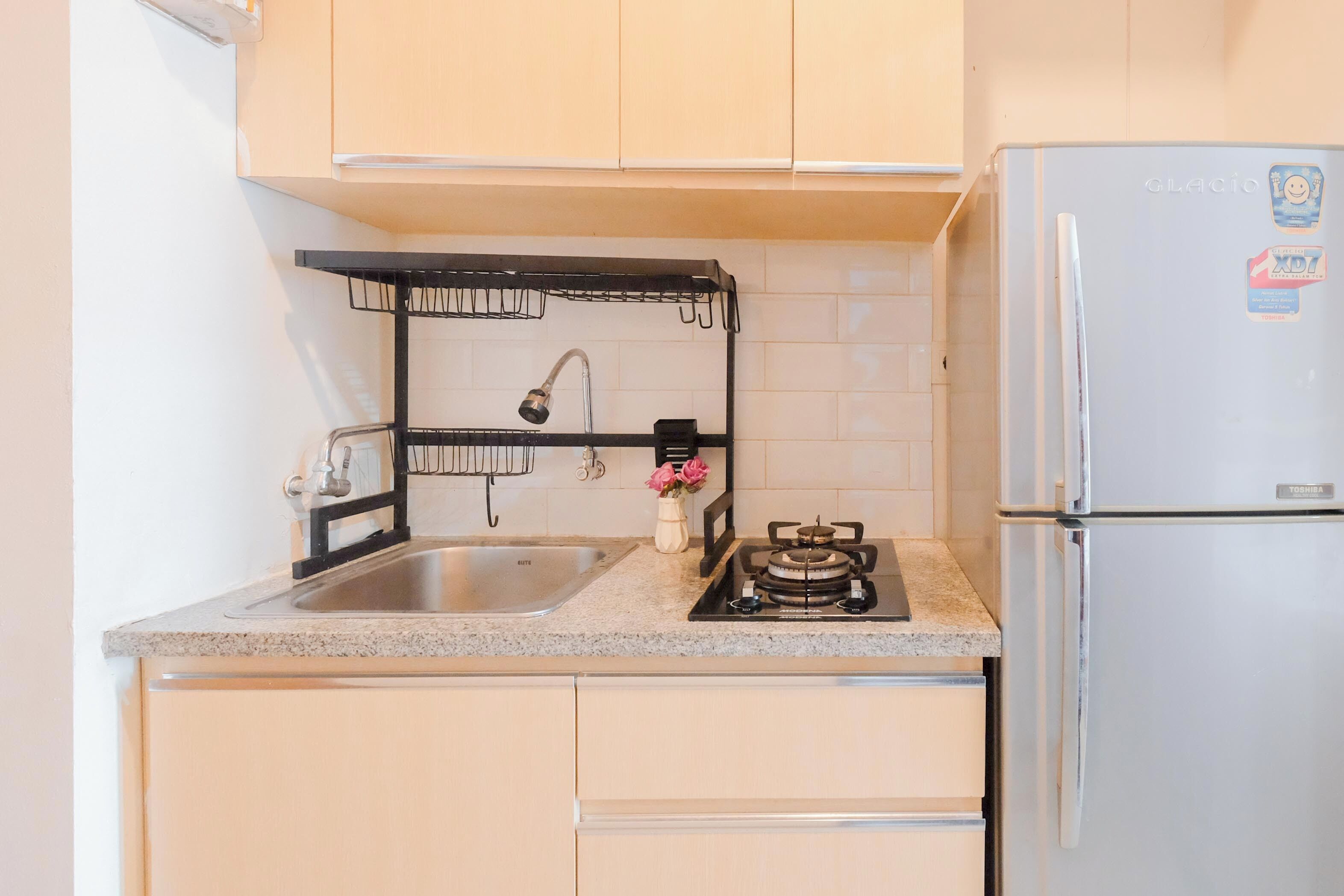 A compact kitchen with a stainless steel sink, a gas stove, and a refrigerator.