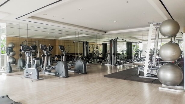 A modern gym with various exercise equipment, including treadmills, ellipticals, and free weights. - Warm 3Br Direct Access To Mall La Riz Supermall Mansion Apartment (Surabaya)