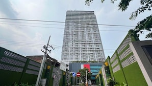 A tall, modern building with a grid-like facade, surrounded by greenery and a clear sky. - Simply Design Studio At Taman Melati Surabaya Apartment (Surabaya)