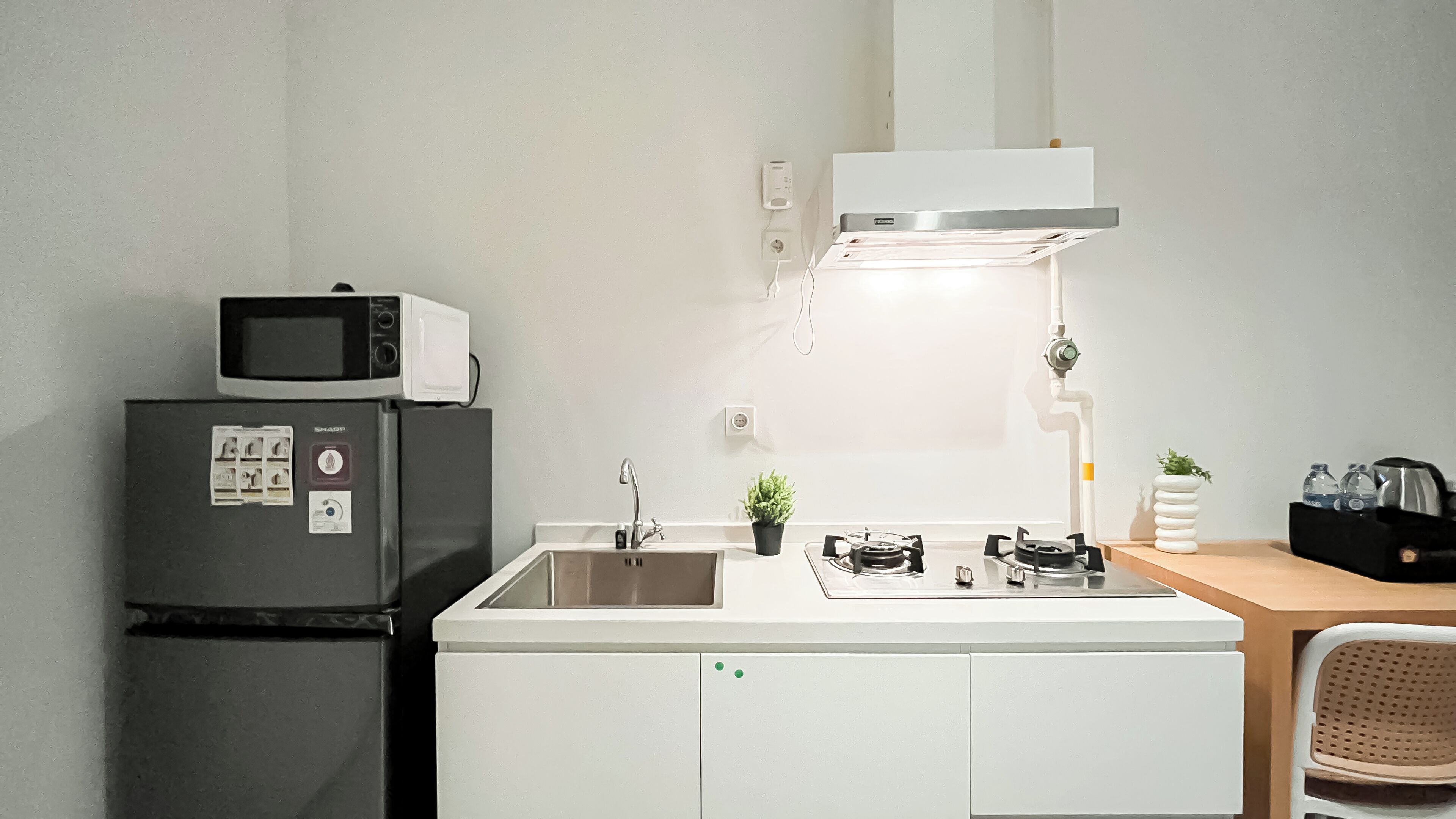 A compact kitchen with a refrigerator, microwave, sink, and gas stove.