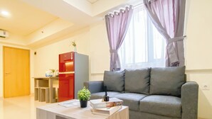 Un salon moderne avec un canapé gris, une table basse en bois et un appareil électroménager rouge en arrière-plan.