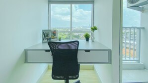 Een kleine kantoorruimte met een bureau, stoel en een raam met uitzicht op de stad.