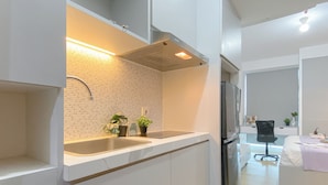 Een moderne keuken met een roestvrijstalen spoelbak, een inbouwoven en een koelkast. Op het aanrecht staan twee planten in potten.