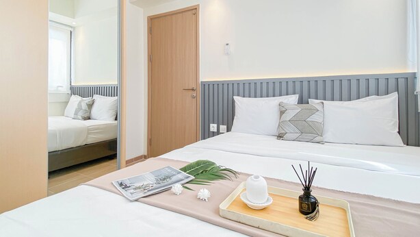 A modern hotel room with a bed, bedside table, and a mirror. - Modern Style 2Br Apartment At Meikarta (Cikarang)