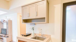 A modern kitchen with wooden cabinets, a built-in sink, and a small countertop. - Simple Look 2Br Apartment Meikarta (Cikarang)