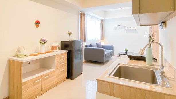 A modern kitchen with a built-in oven, a sink, and a dining area with a sofa and a table. - Simple Look 2Br Apartment Meikarta (Cikarang)