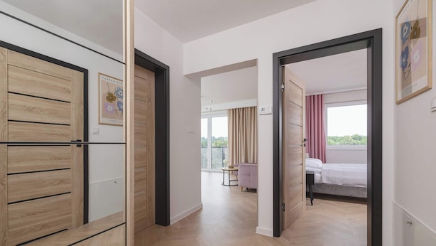 Quarto de hotel moderno com guarda-roupa de madeira, uma cama, uma mesinha e vista para o exterior.