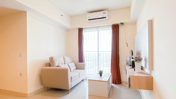 Una sala de estar moderna con un sofá, una mesa de centro y un televisor sobre un mueble.
