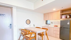 Una cocina moderna con armarios de madera, un refrigerador de acero inoxidable y una zona de comedor con una mesa y sillas de madera.
