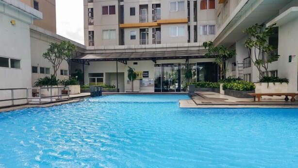 A swimming pool with a covered area, surrounded by buildings with balconies and windows. - Studio Apartment Near Kebayoran Station At Pakubuwono Terrace (Jakarta)
