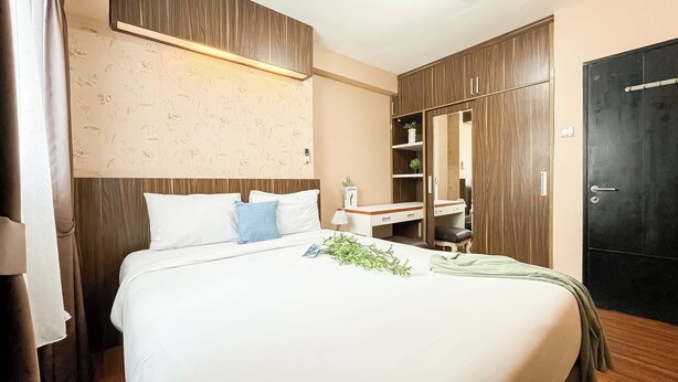 A hotel room with a bed, a nightstand, a wardrobe, and a door. - Cozy 1Br Apartment At The Wave Kuningan (Jakarta)