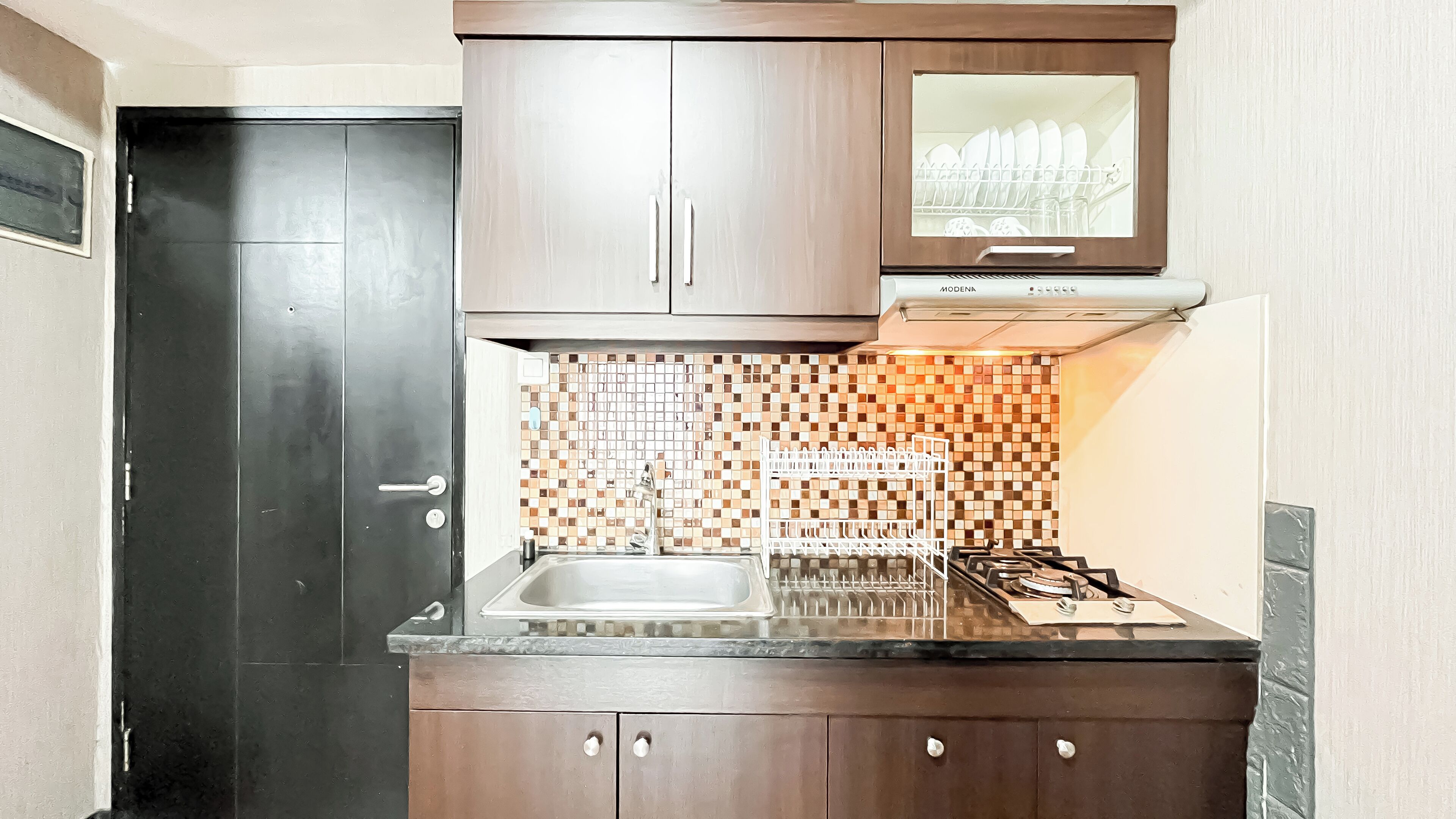 A kitchen with a stainless steel sink, a tiled backsplash, and a gas stove.
