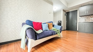 A modern living room with a sofa, a coffee machine, and a kitchen area. - Cozy 1Br Apartment At The Wave Kuningan (Jakarta)