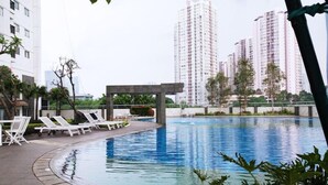A swimming pool with lounge chairs and a covered seating area, surrounded by high-rise buildings. - Cozy 1Br Apartment At The Wave Kuningan (Jakarta)