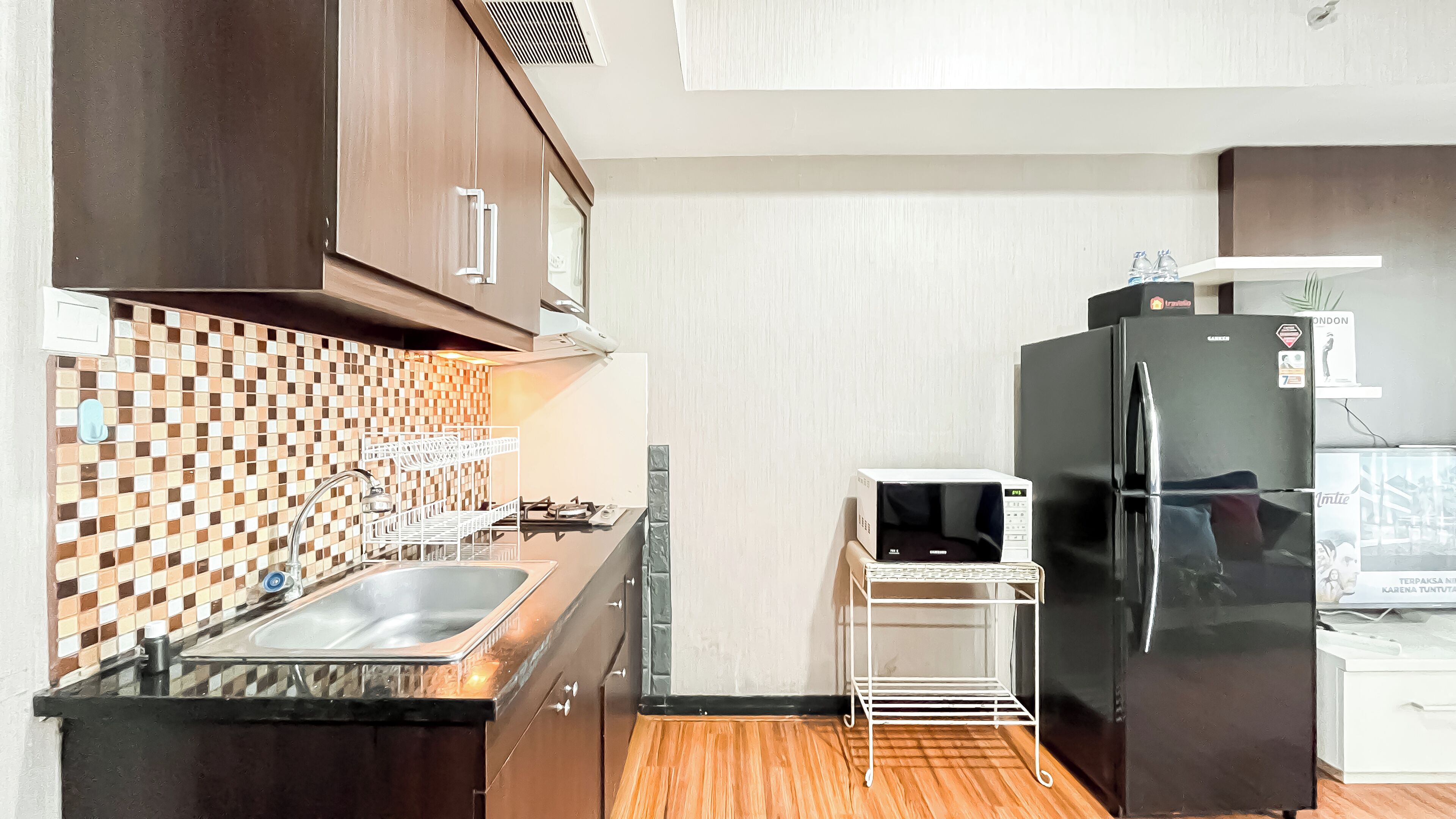 A kitchen with a sink, a microwave, and a black refrigerator.