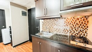 A compact kitchen with a built-in gas stove, a stainless steel sink, and a tiled backsplash. - Cozy 1Br Apartment At The Wave Kuningan (Jakarta)