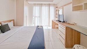 A hotel room with a bed, a desk, a television, and a window with curtains.