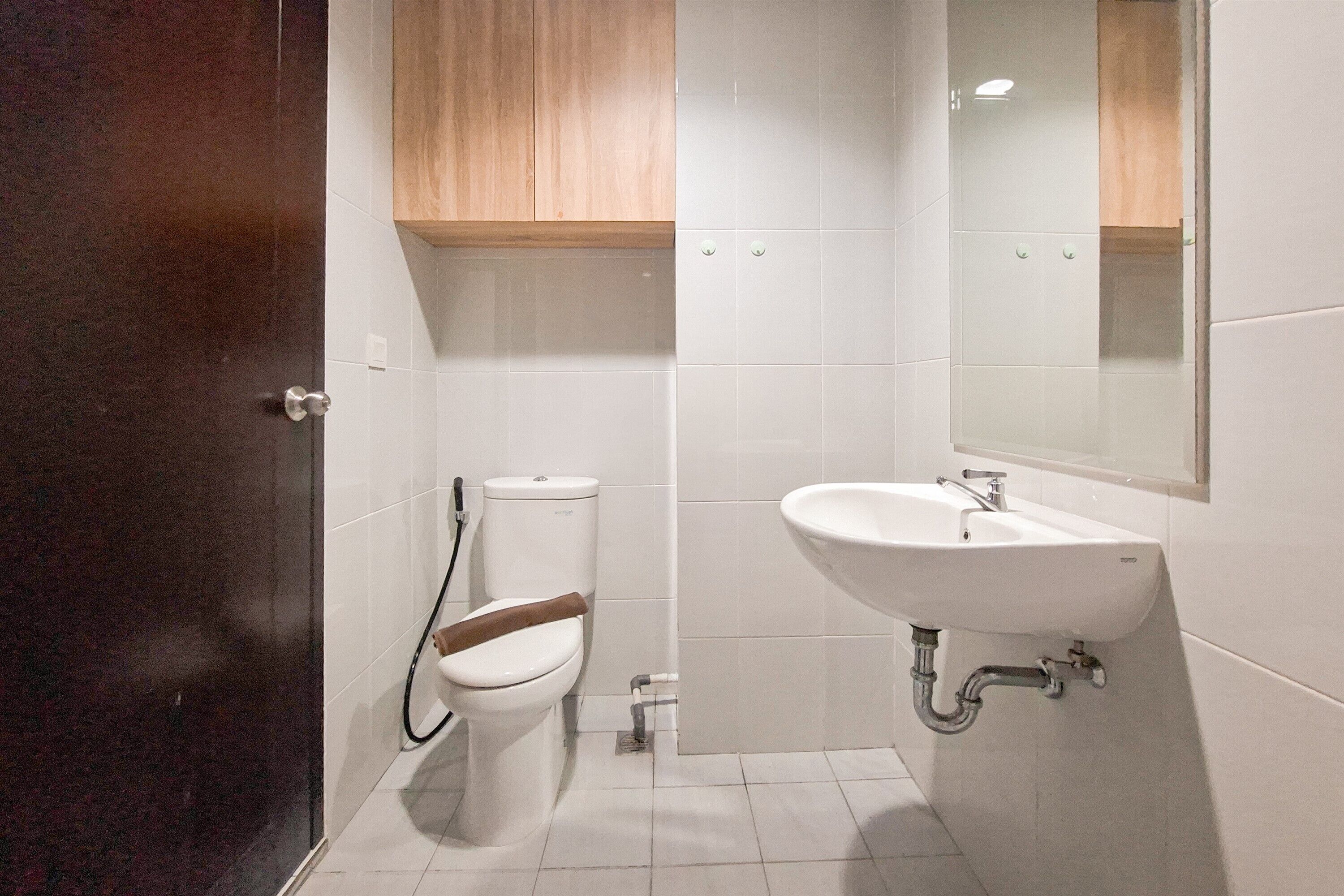 A bathroom with a toilet, sink, and wooden cabinet.