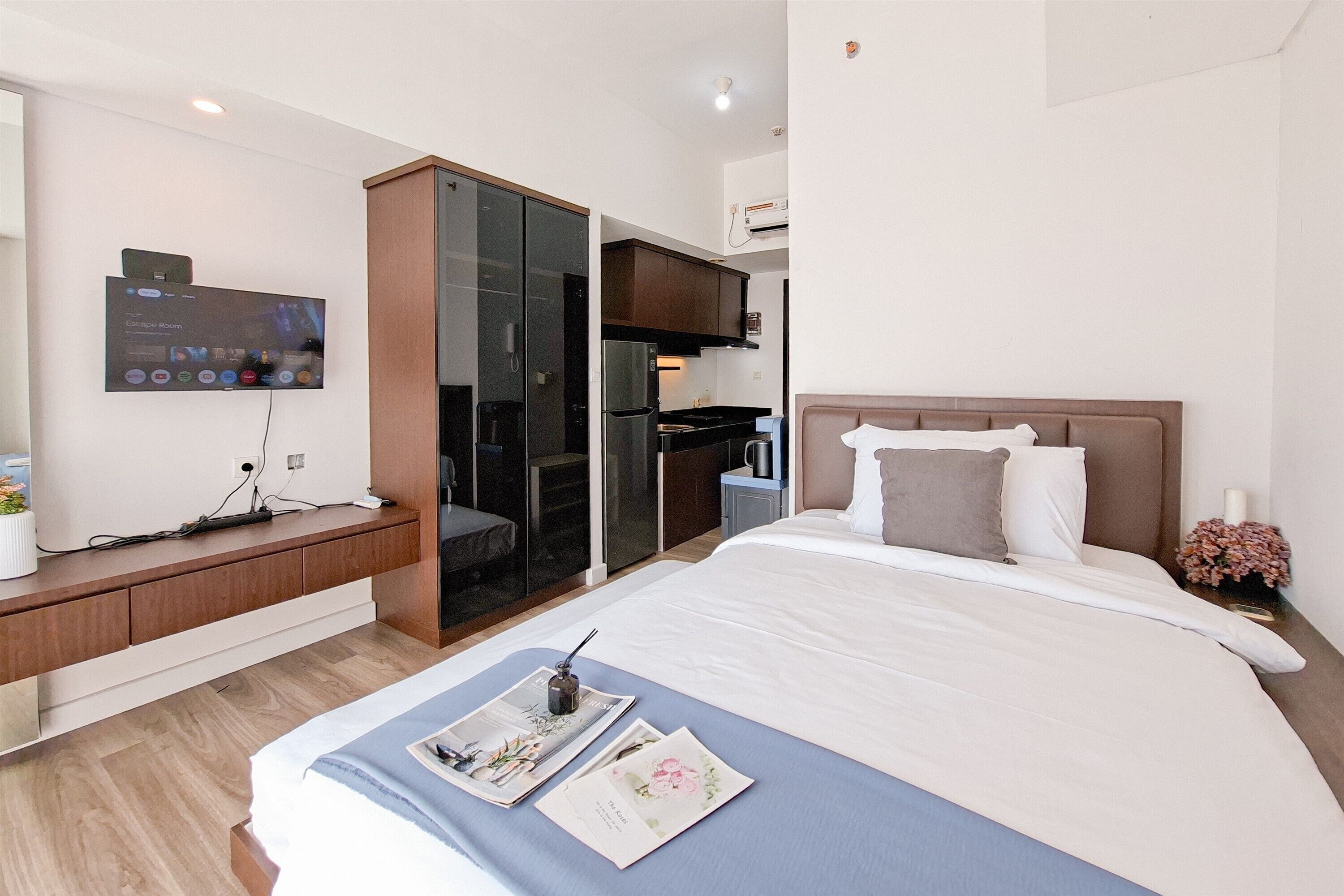 A modern hotel room with a bed, a desk with a computer, a TV, and a sliding closet door.