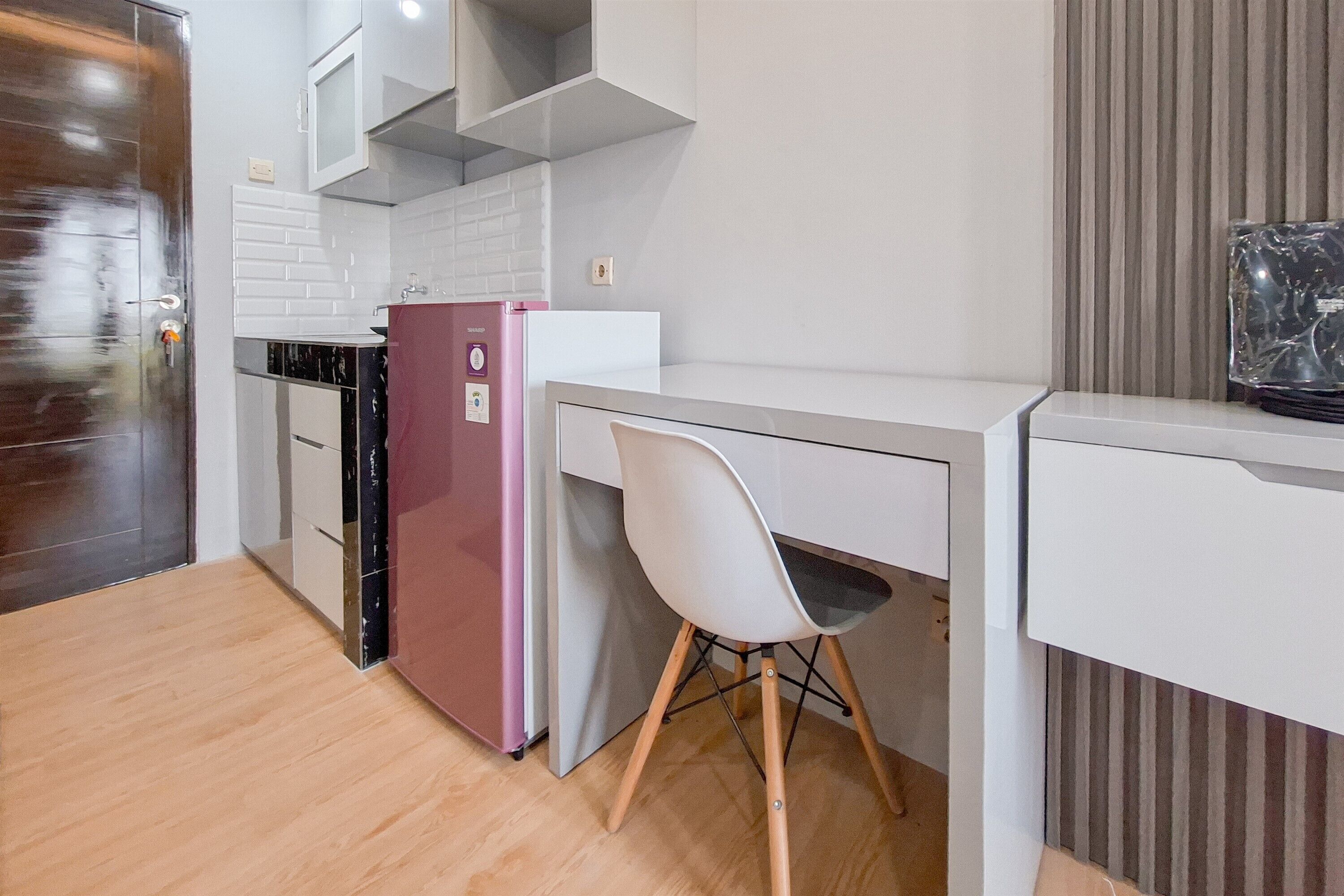 A compact kitchen with a refrigerator, a sink, and a chair.