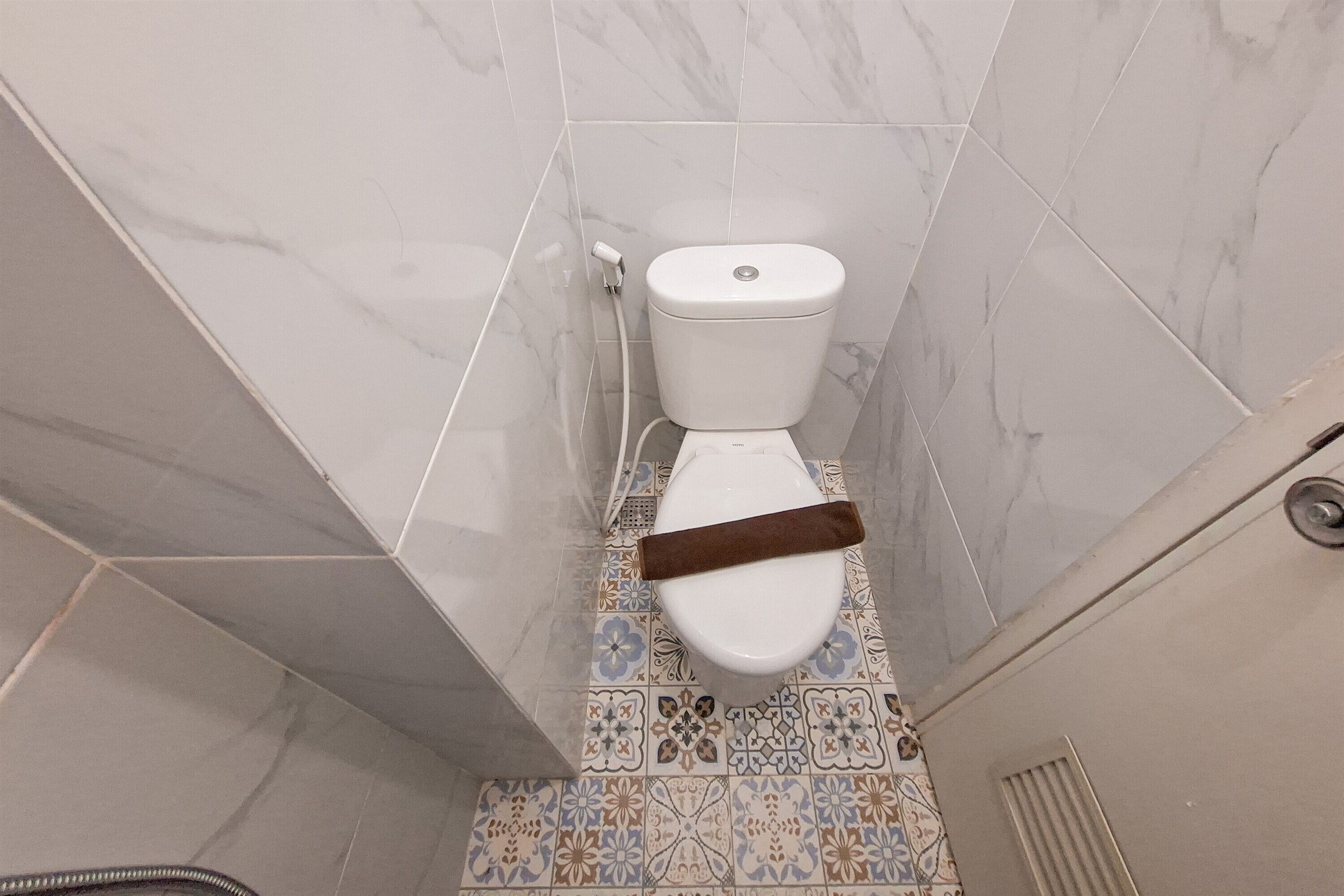A bathroom with a toilet, a shower, and a tiled floor with a geometric pattern.