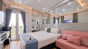 Ein modernes Schlafzimmer mit einem Bett, einem rosa Sofa, einem Schreibtisch und einem Fernseher.