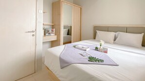 Een hotelkamer met een bed, een kledingkast, een nachtkastje en een spiegel.