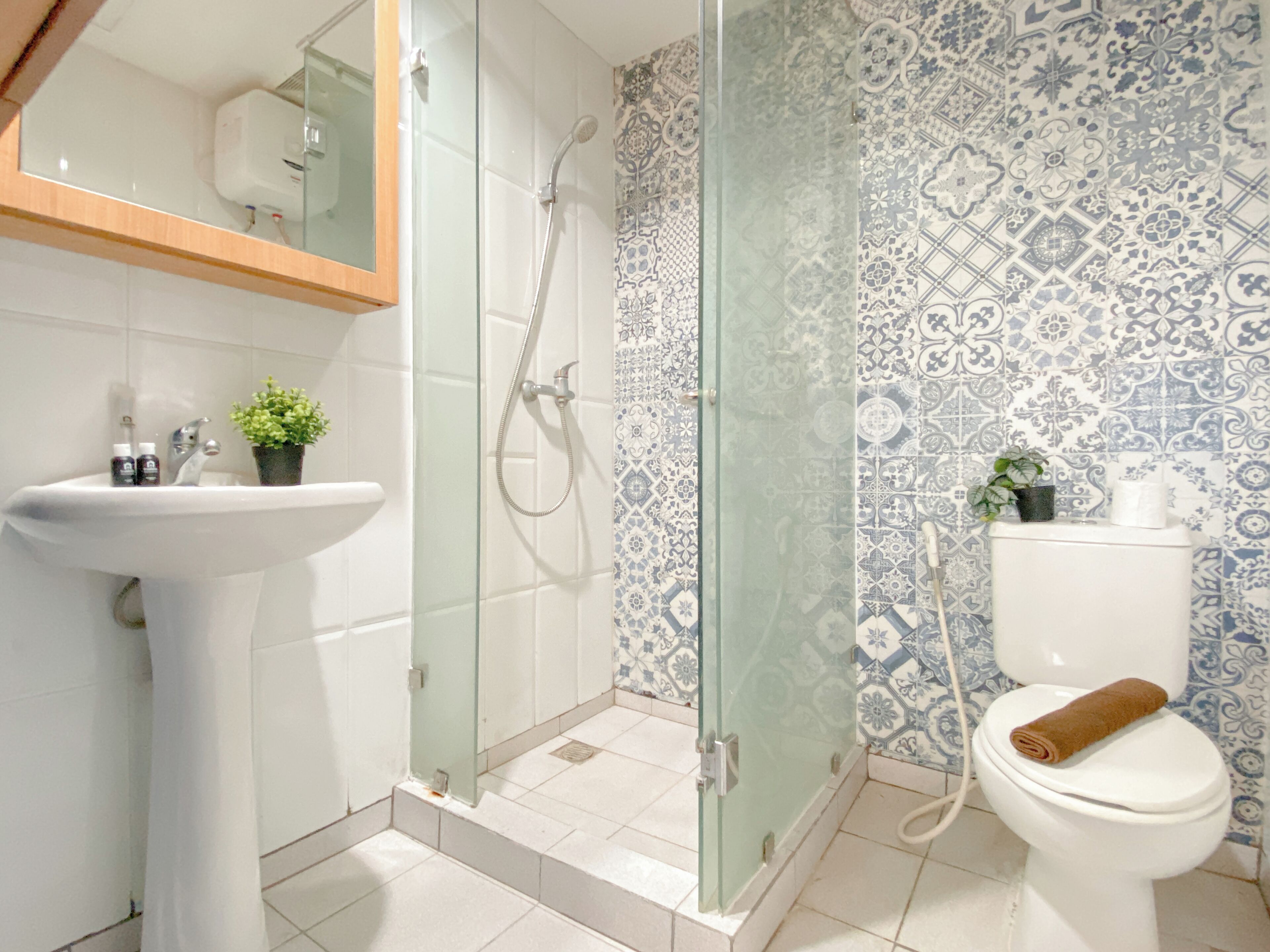 A bathroom with a glass-enclosed shower, a white sink, and a toilet with a towel on it.
