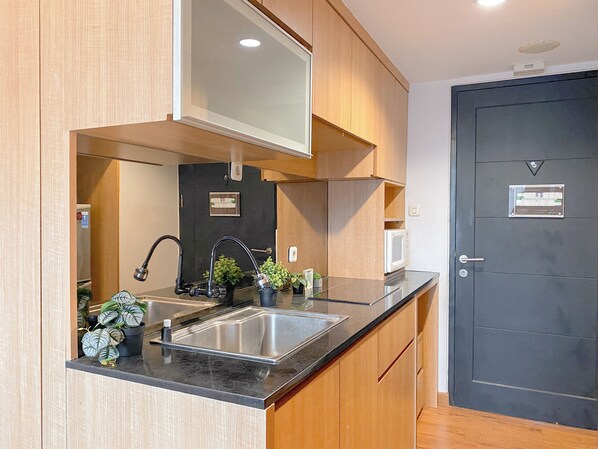A compact kitchen with a sink, a microwave, and wooden cabinets.