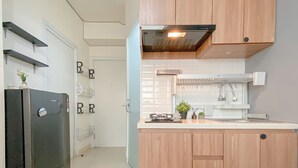 A modern kitchen with wooden cabinets, a black refrigerator, a built-in oven, and a stainless steel sink. - Compact 2Br Apartment Direct Access To Mall At Green Pramuka City (Jakarta)