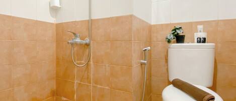 A bathroom with a shower, toilet, and a small potted plant on the toilet.