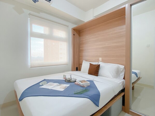 A modern bedroom with a wooden headboard, a large window, and a neatly made bed with a blue throw blanket and pillows.