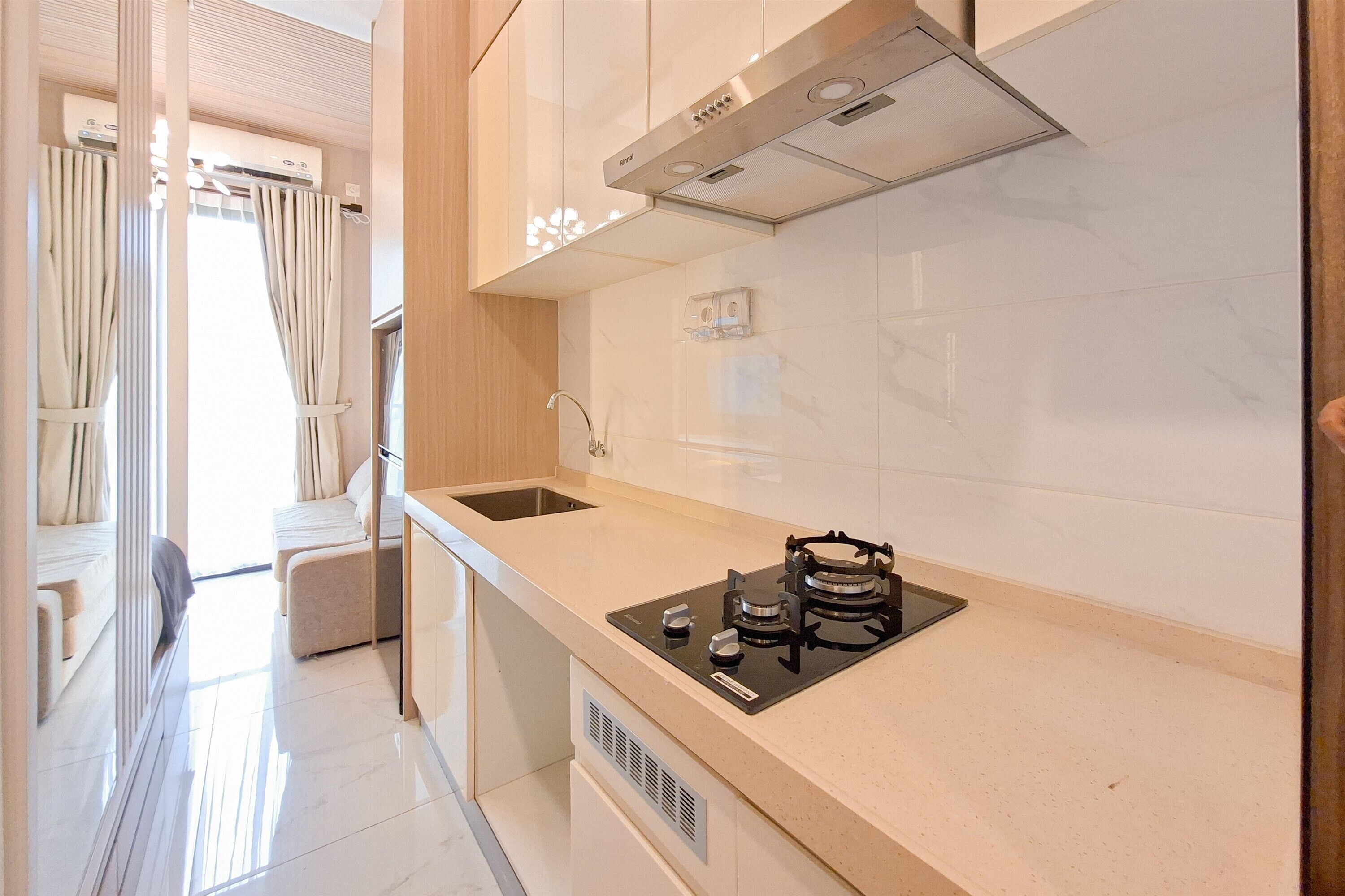 Una cocina moderna con estufa a gas, un lavamanos y un ventanal con cortinas.
