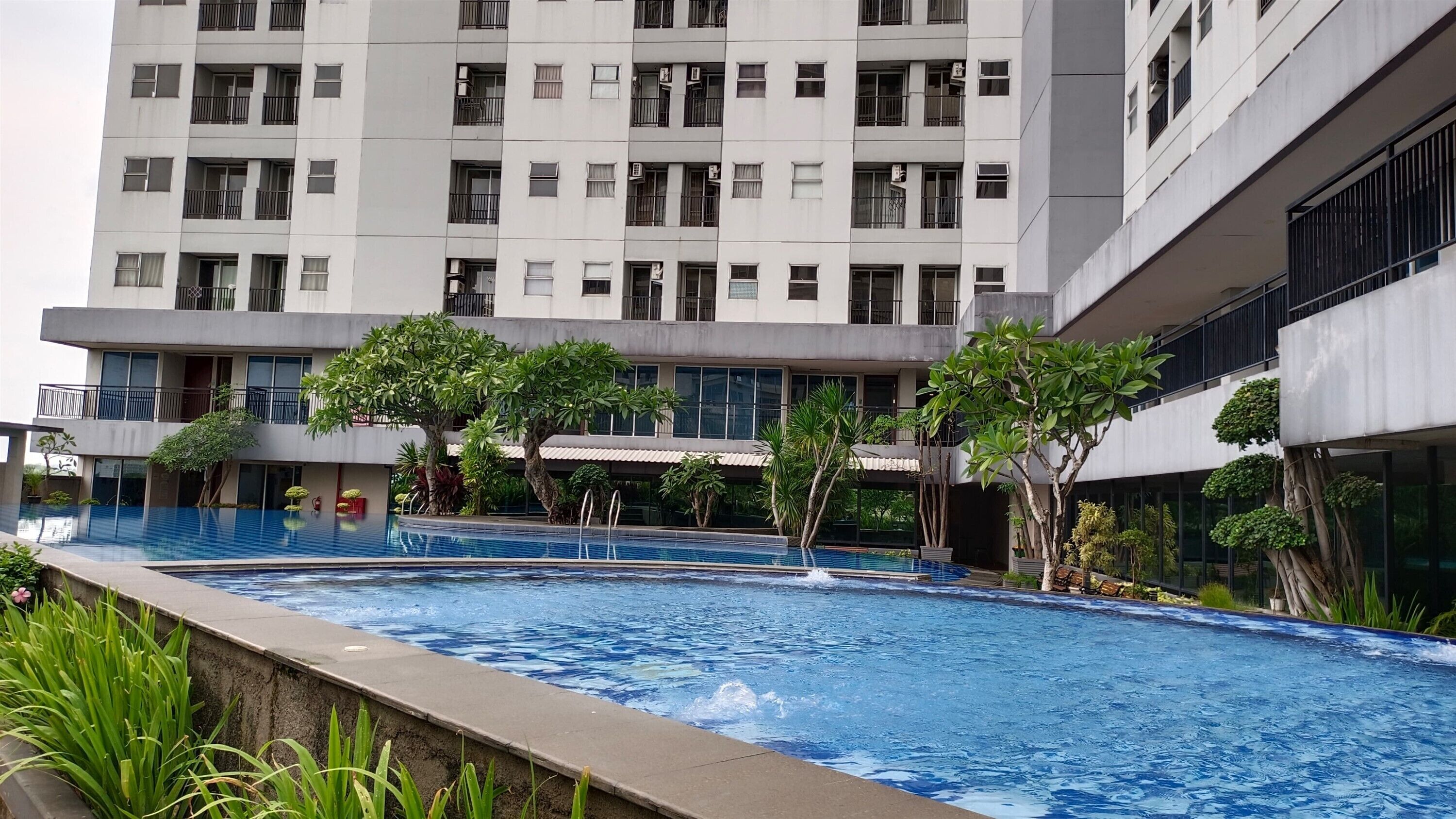 A modern building with multiple balconies and a swimming pool area.