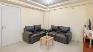 A living room with two dark leather sofas, a wooden coffee table, and a white door. - Combined 1Br With Extra Room Apartment At Green Pramuka City (Jakarta)