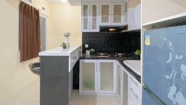 A compact kitchen with white cabinets, a black countertop, and a built-in oven. - Combined 1Br With Extra Room Apartment At Green Pramuka City (Jakarta)