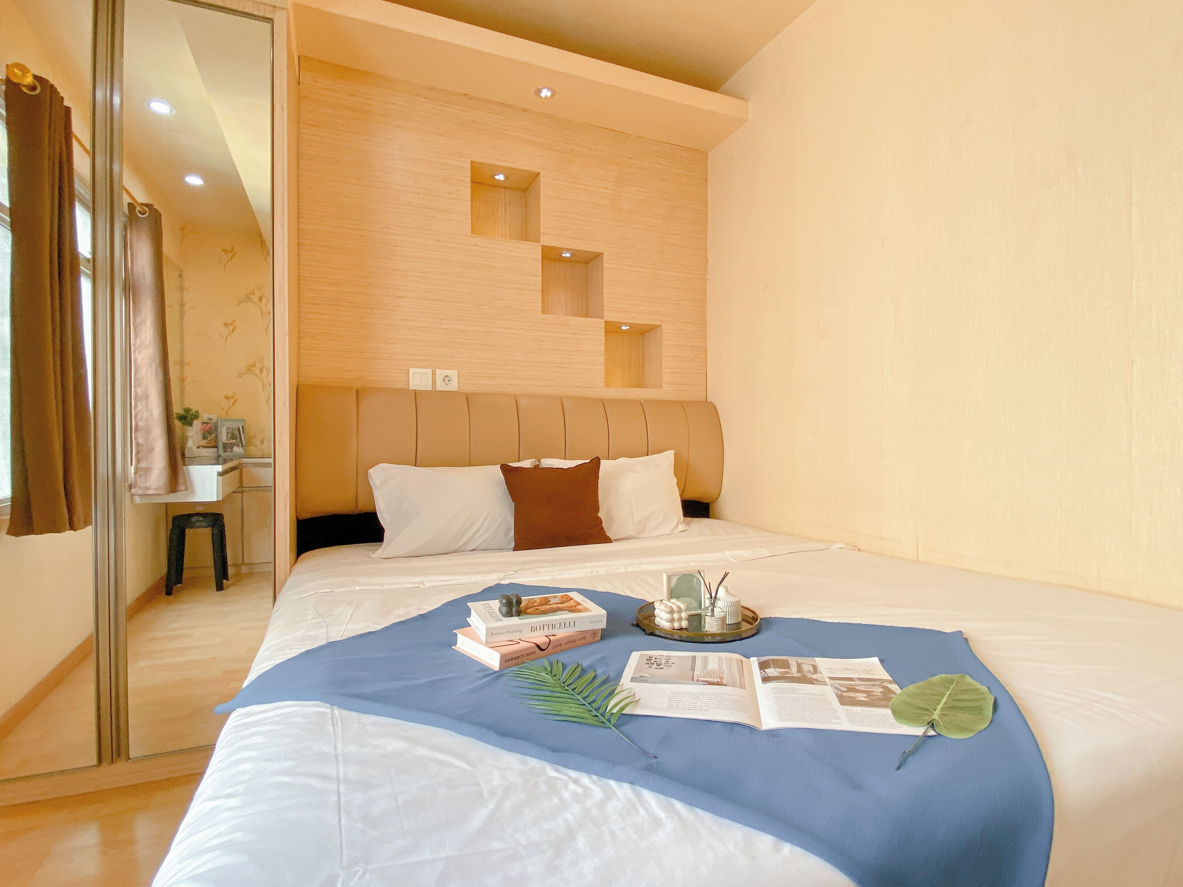 A modern hotel room with a large bed, a bedside table, and a mirror.