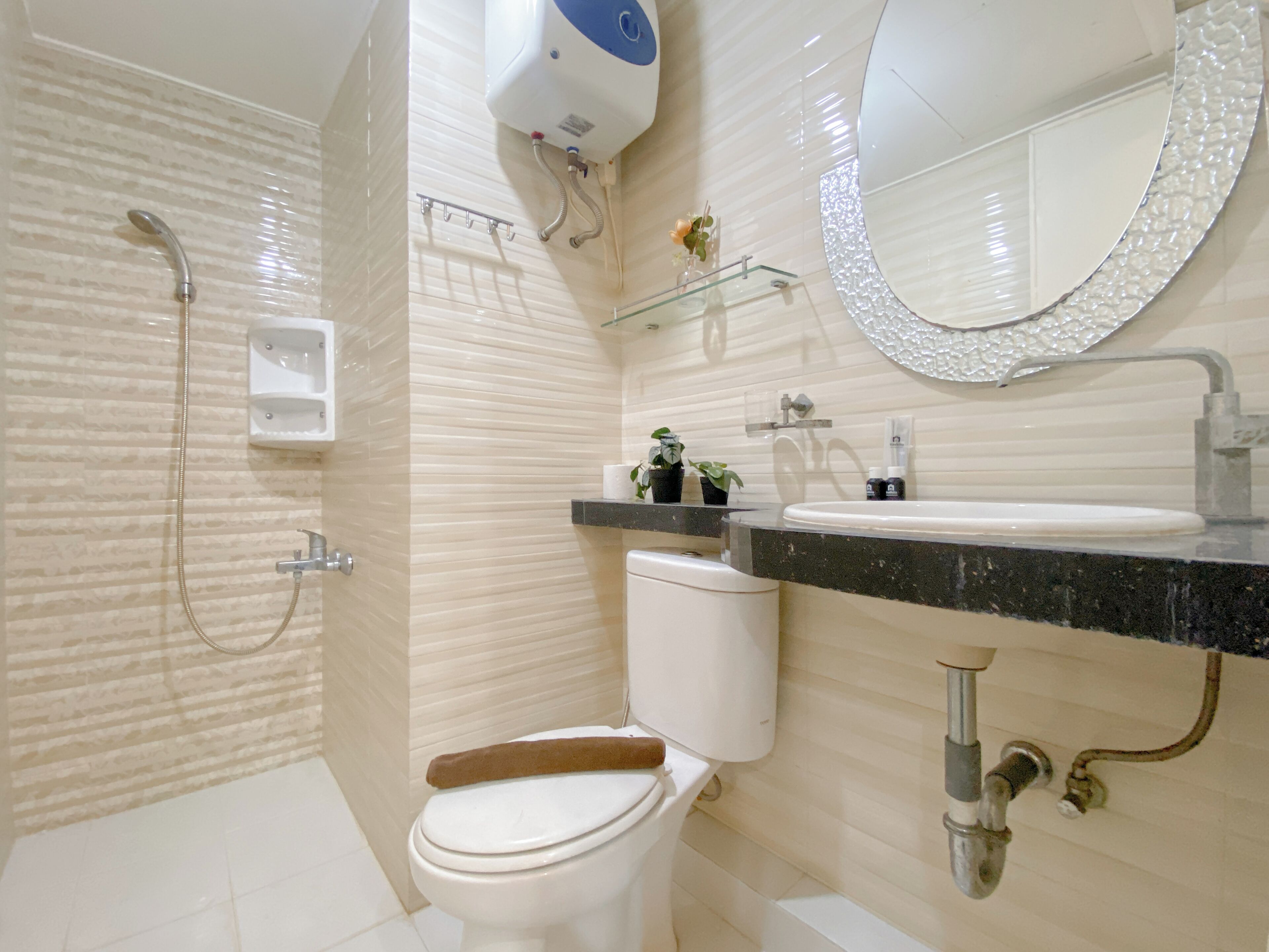 A modern bathroom with a toilet, sink, shower, and a glass shelf with toiletries.