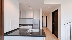 A modern kitchen with a black countertop, white cabinets, and a built-in refrigerator. - Modern Contemporary Cozy 2Br At Branz Bsd City Apartment (Pagedangan)